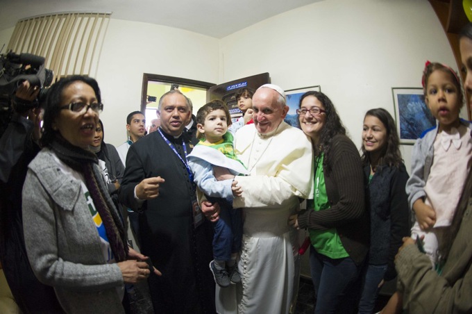 Handout shows Pope Francis holding a boy while on a visit to the Varginha slum in Rio de Janeiro